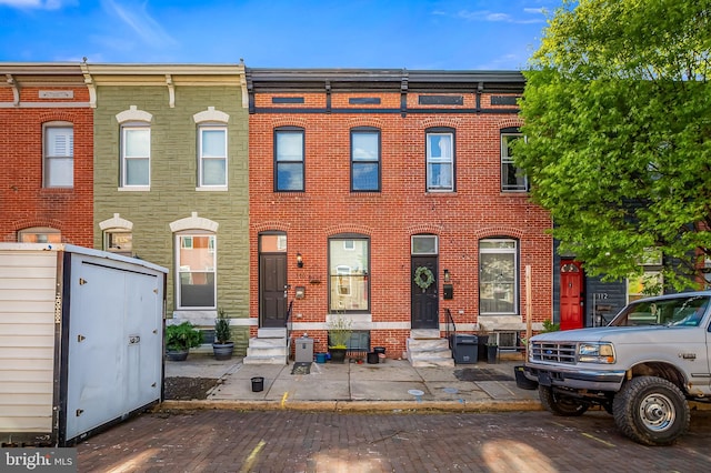 townhome / multi-family property featuring uncovered parking, entry steps, and brick siding