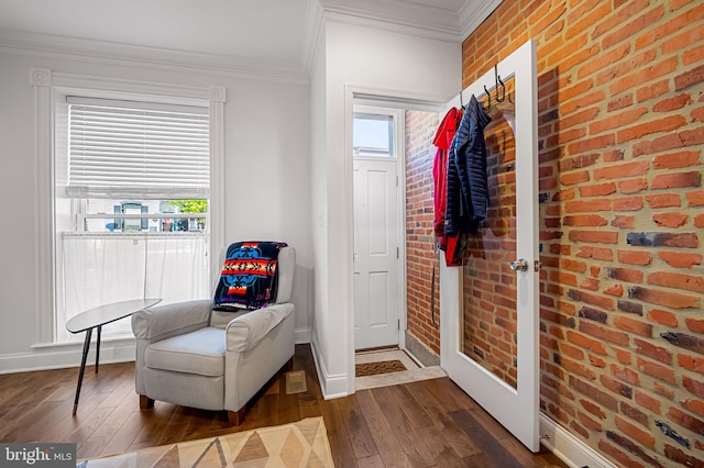 sitting room with brick wall, baseboards, ornamental molding, and dark wood-type flooring