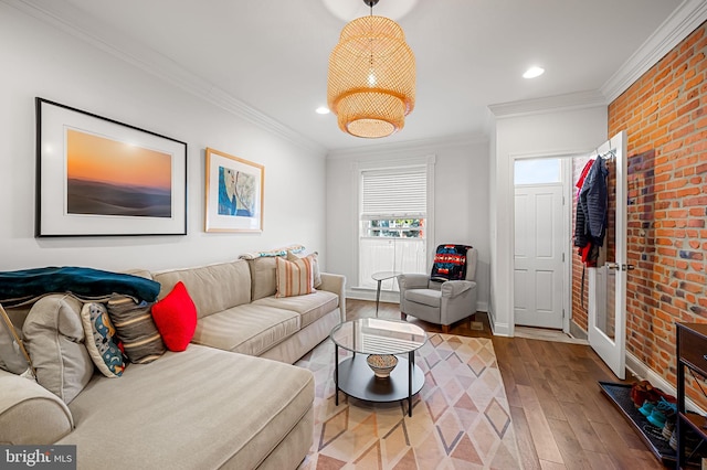 living room with crown molding, hardwood / wood-style flooring, and brick wall