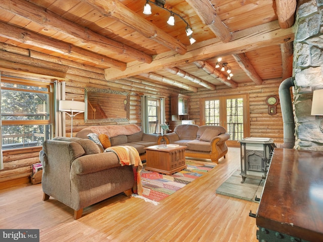 living area featuring a wood stove, log walls, wood ceiling, hardwood / wood-style flooring, and rail lighting