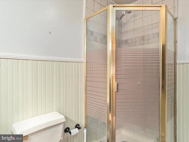 full bathroom with wainscoting, toilet, and a shower stall