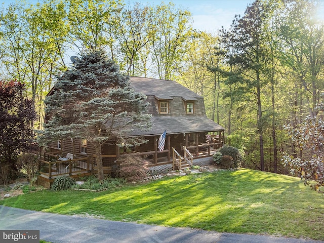 view of front of home featuring a shingled roof, covered porch, and a front yard