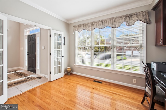 foyer featuring visible vents, light wood-style flooring, a healthy amount of sunlight, and crown molding