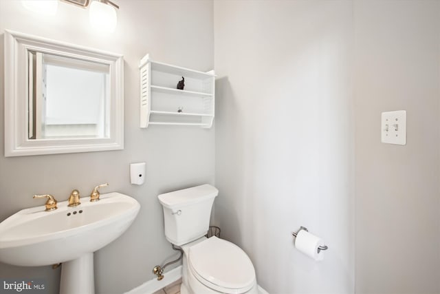 bathroom with a sink, toilet, and baseboards