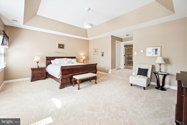 bedroom with visible vents, baseboards, light carpet, and a tray ceiling