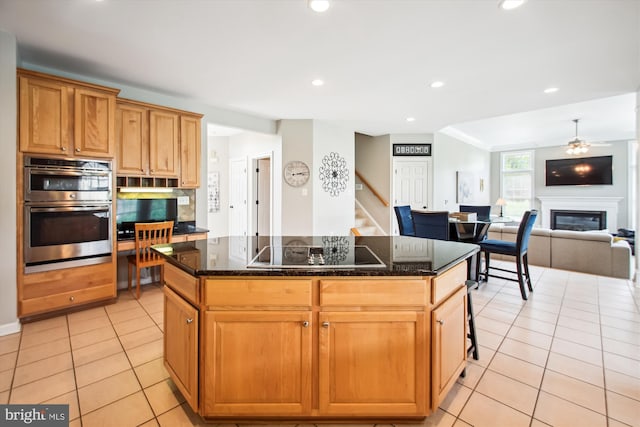 kitchen featuring recessed lighting, light tile patterned floors, black electric stovetop, a kitchen island, and double oven