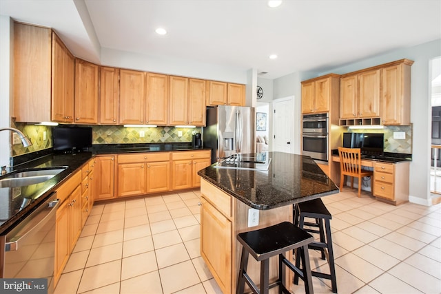 kitchen with a sink, stainless steel appliances, light tile patterned floors, a breakfast bar area, and backsplash