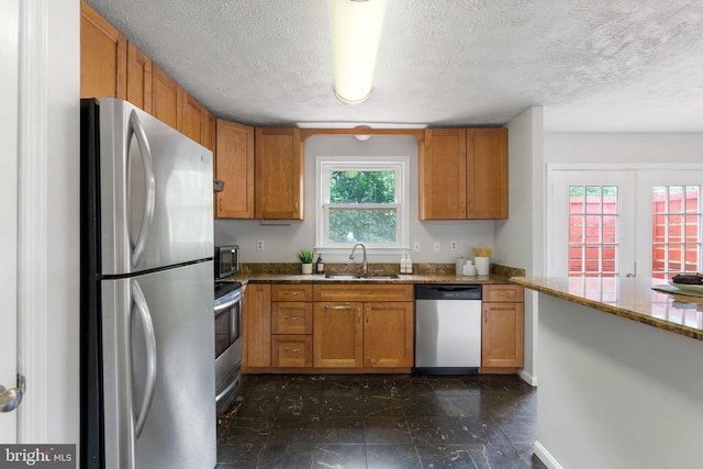 2116 Bell Tree Ln, Waldorf, MD 20601 - kitchen with appliances with stainless steel finishes, a sink, a textured ceiling, light stone countertops, and brown cabinets