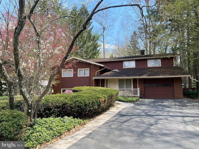 490 Orlando Ave, State College, PA 16803 - split level home featuring asphalt driveway, a garage, a chimney, and brick siding
