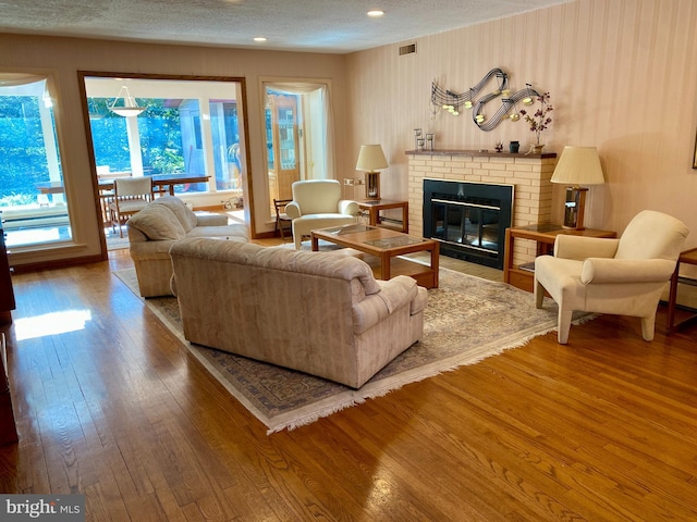490 Orlando Ave, State College, PA 16803 - living area with wood-type flooring, a brick fireplace, a textured ceiling, and recessed lighting