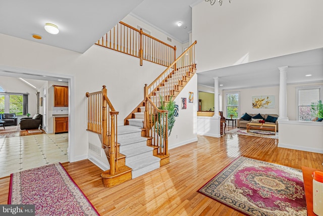 stairway with plenty of natural light, decorative columns, and wood finished floors
