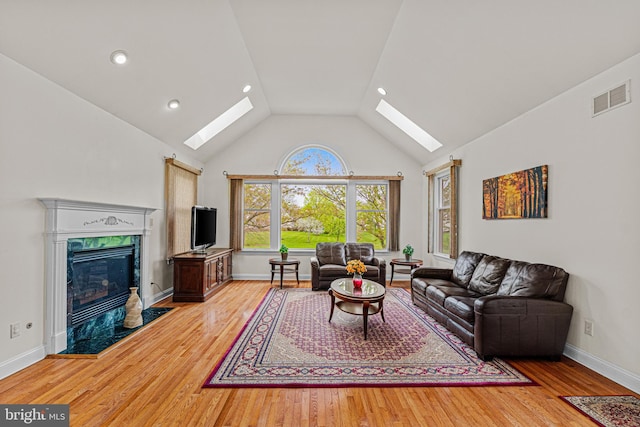 living area featuring a skylight, wood finished floors, visible vents, and a fireplace