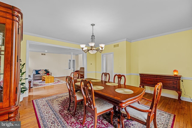dining area with wood-type flooring, a chandelier, and crown molding