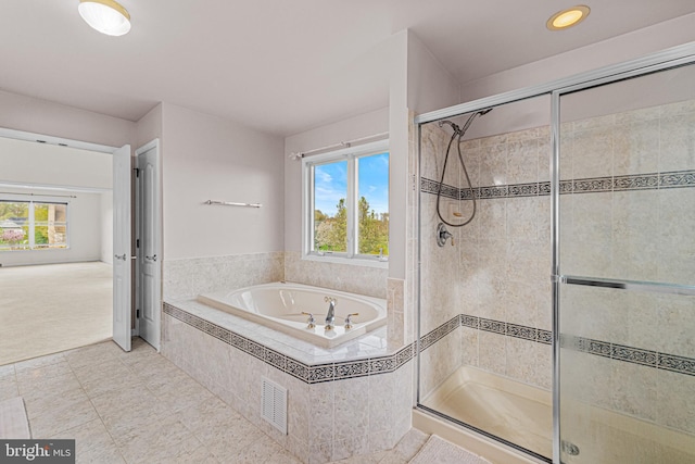 bathroom featuring a shower stall, plenty of natural light, and a garden tub