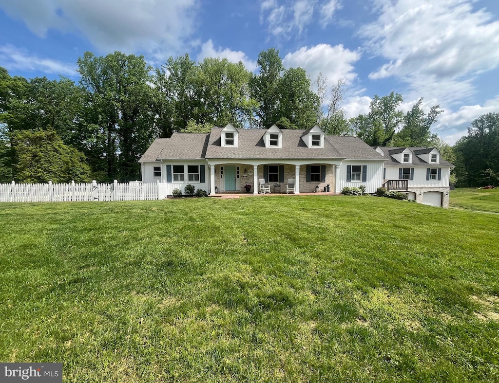 view of front of property with an attached garage, a front lawn, fence, and covered porch