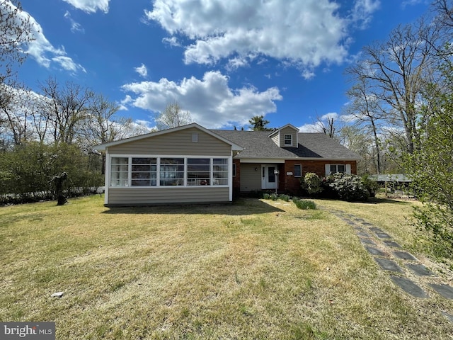rear view of house featuring a lawn, a shingled roof, and a sunroom