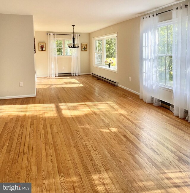unfurnished dining area featuring baseboards, a baseboard heating unit, and light wood-style flooring