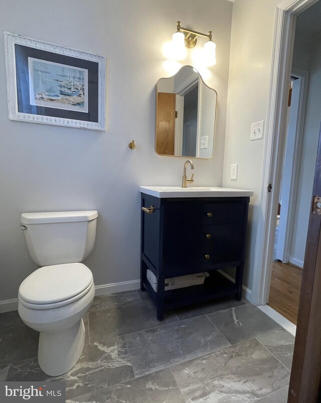 bathroom with baseboards, vanity, and toilet