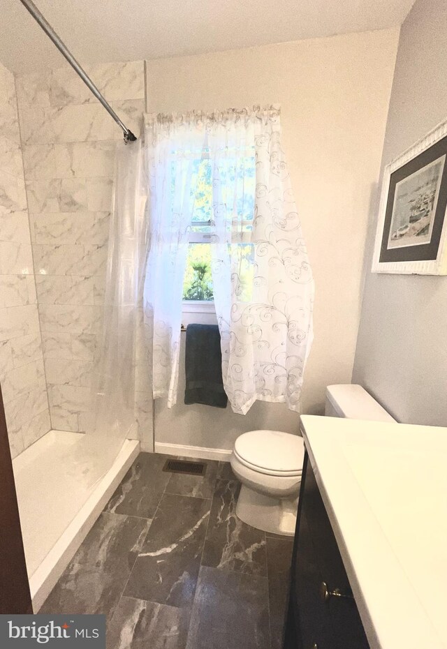 bathroom featuring vanity, toilet, marble finish floor, and a stall shower