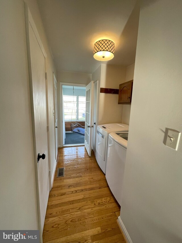 laundry room with cabinet space, washing machine and clothes dryer, light wood-style floors, french doors, and visible vents