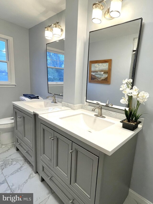 full bath featuring double vanity, a sink, marble finish floor, and a wealth of natural light