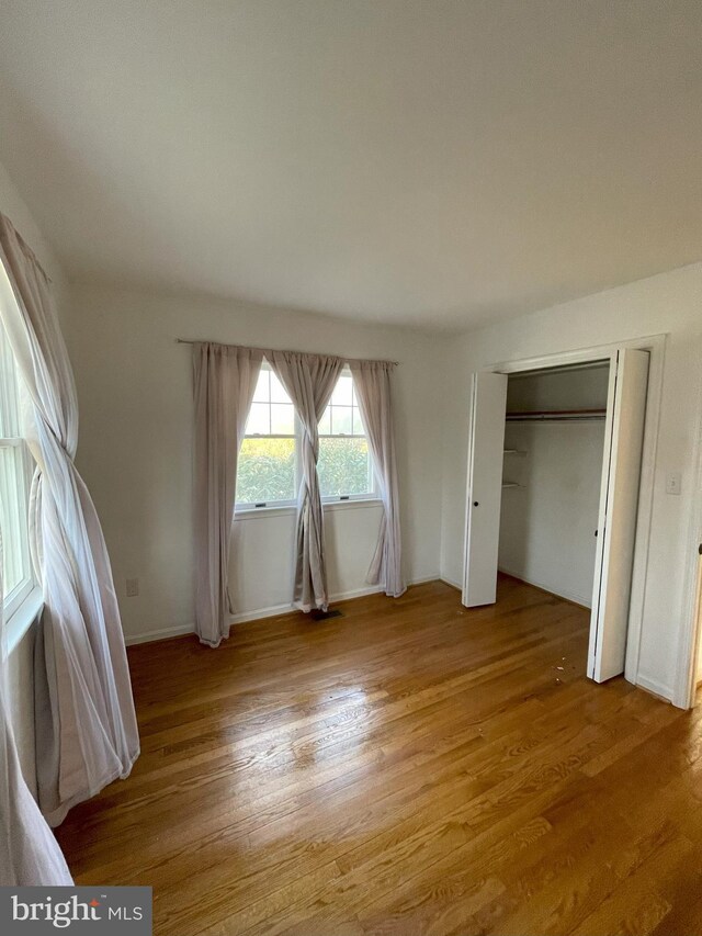 unfurnished bedroom featuring baseboards, light wood-style flooring, and a closet