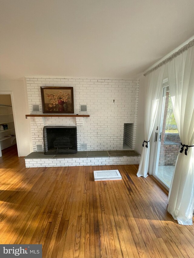 unfurnished living room with a fireplace, wood finished floors, and visible vents