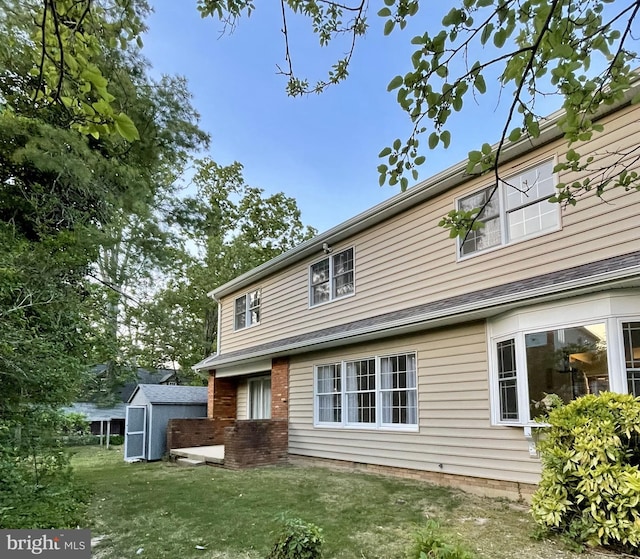 rear view of house featuring a storage shed, a lawn, and an outbuilding