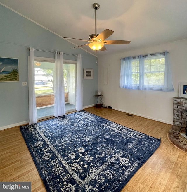 interior space featuring a ceiling fan, vaulted ceiling, wood finished floors, and visible vents