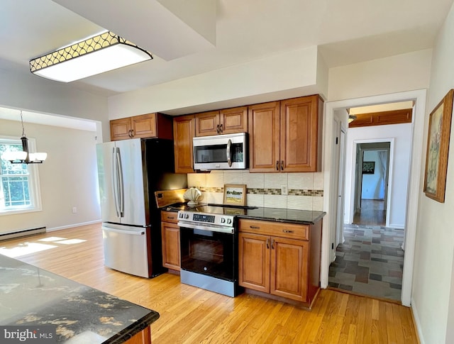 kitchen with light wood finished floors, backsplash, brown cabinets, and stainless steel appliances