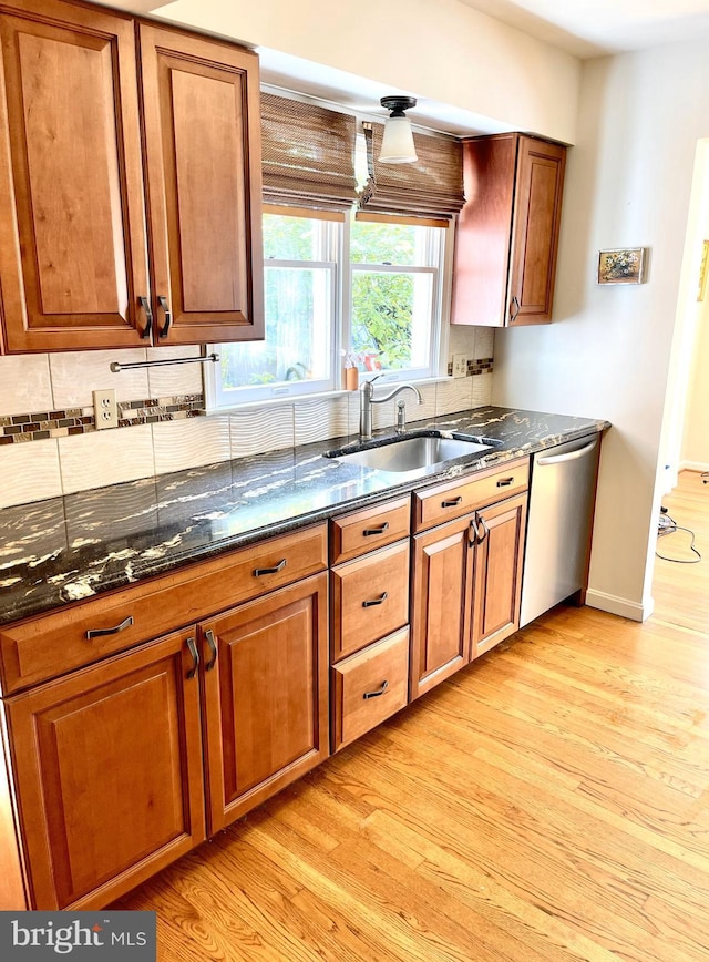 kitchen with decorative backsplash, a sink, light wood finished floors, and dishwasher