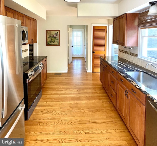 kitchen with appliances with stainless steel finishes, plenty of natural light, light wood-style flooring, and a sink