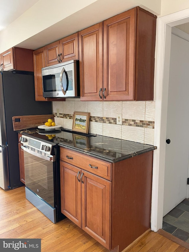 kitchen featuring appliances with stainless steel finishes, decorative backsplash, brown cabinets, and light wood-style flooring