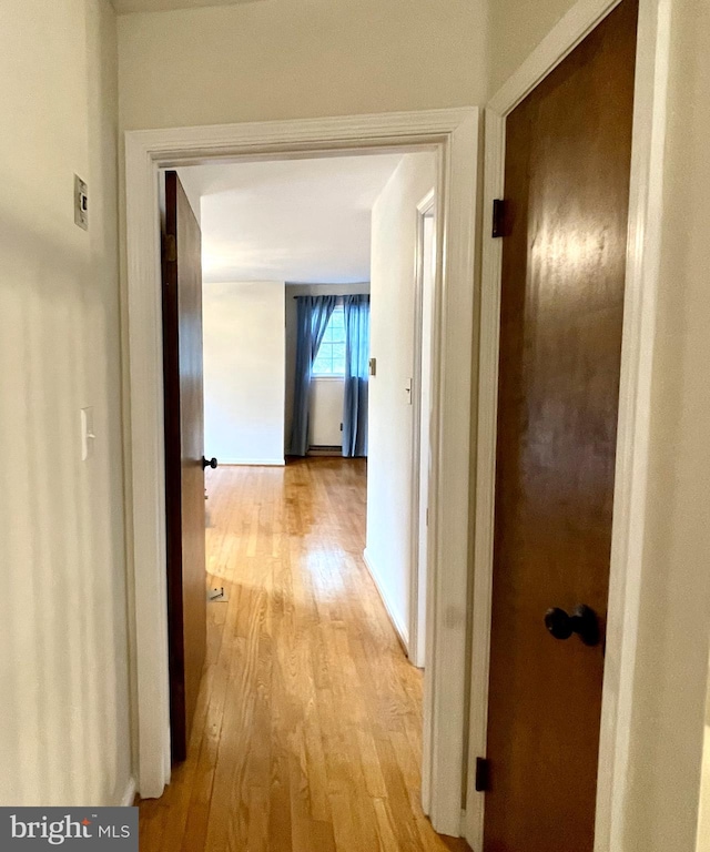 hallway featuring baseboards and light wood finished floors