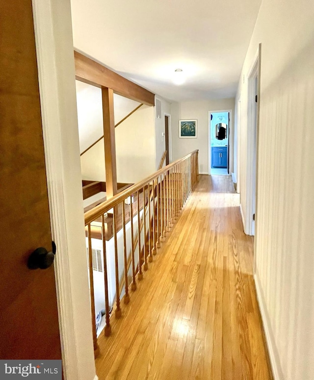 corridor featuring visible vents, an upstairs landing, and hardwood / wood-style floors