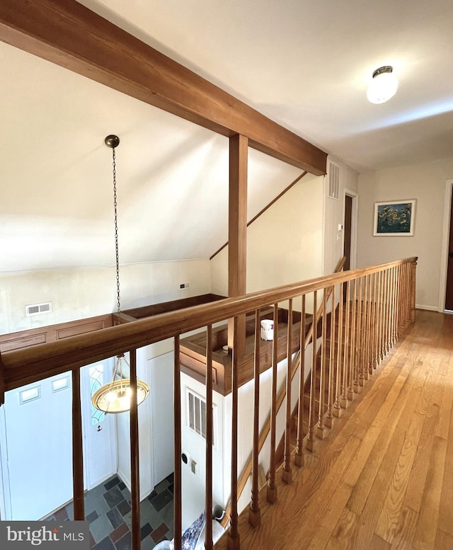 hallway featuring visible vents, wood finished floors, and an upstairs landing