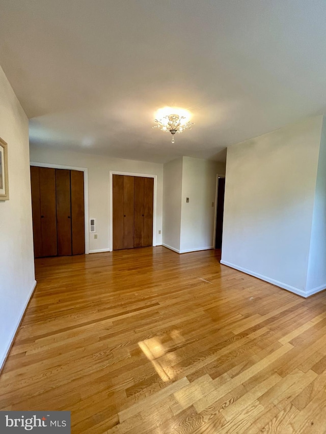 spare room featuring baseboards and light wood-type flooring