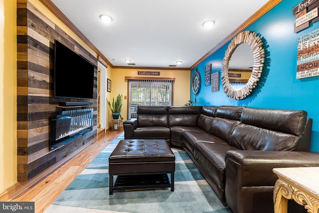 living area with ornamental molding, a glass covered fireplace, wood finished floors, and recessed lighting