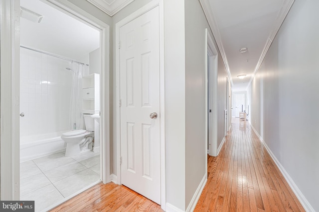 corridor featuring baseboards, crown molding, visible vents, and light wood-style flooring