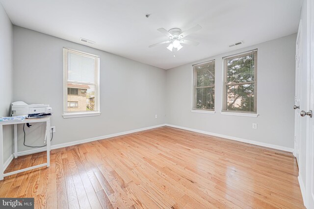 spare room featuring hardwood / wood-style floors, baseboards, a ceiling fan, and visible vents