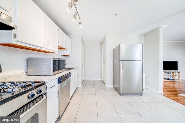 kitchen with decorative backsplash, light tile patterned flooring, appliances with stainless steel finishes, white cabinetry, and under cabinet range hood