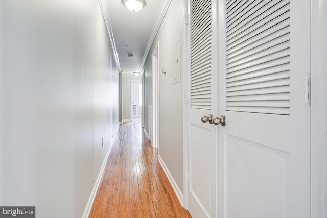 hallway with light wood-type flooring, baseboards, and crown molding