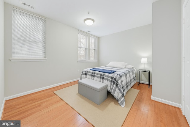 bedroom with light wood finished floors, baseboards, and visible vents