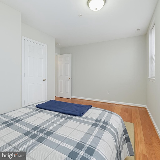 bedroom with visible vents, baseboards, and wood finished floors