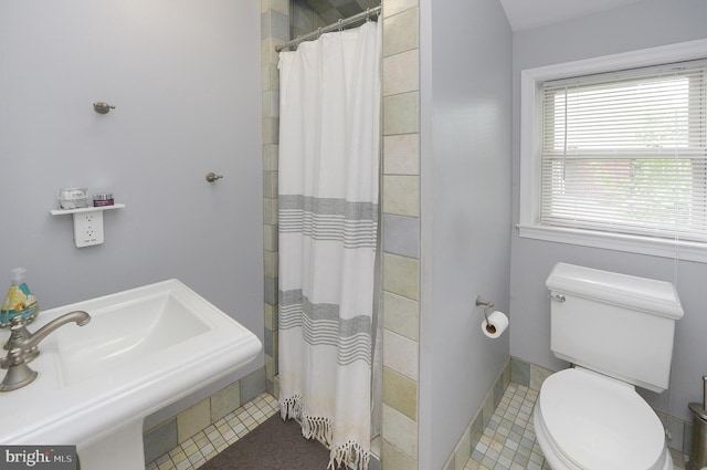 bathroom featuring a sink, a tile shower, and toilet