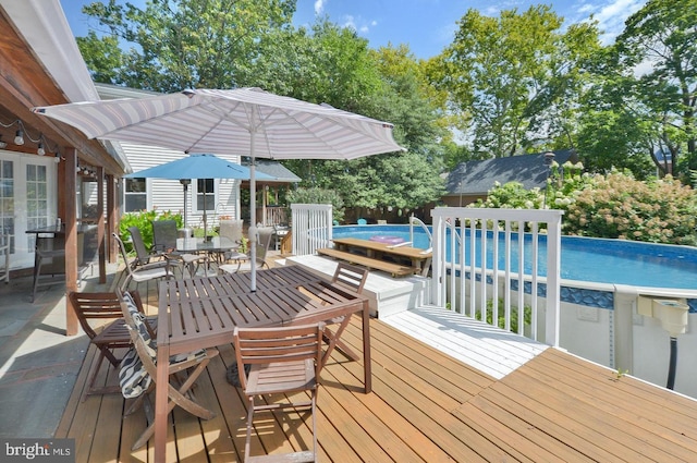 wooden deck with outdoor dining space and an outdoor pool