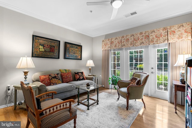 living area with a ceiling fan, visible vents, crown molding, baseboards, and light wood finished floors