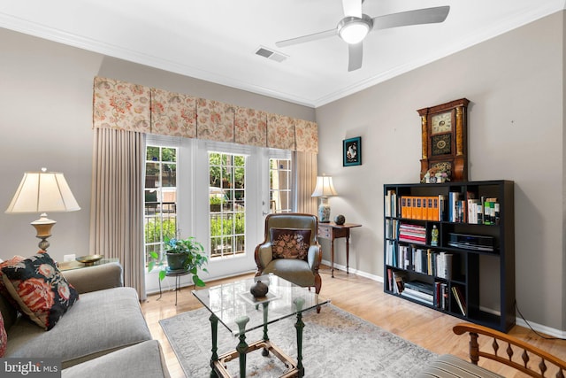 living area with crown molding, a ceiling fan, visible vents, and wood finished floors