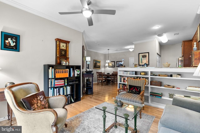 living area featuring baseboards, ornamental molding, light wood finished floors, and ceiling fan