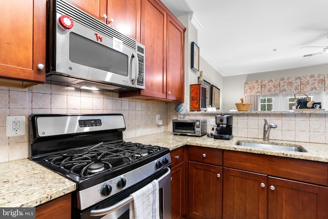 kitchen with appliances with stainless steel finishes, tasteful backsplash, a sink, a toaster, and light stone counters